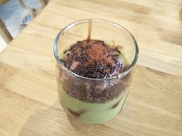a glass filled with a dessert on top of a wooden table
