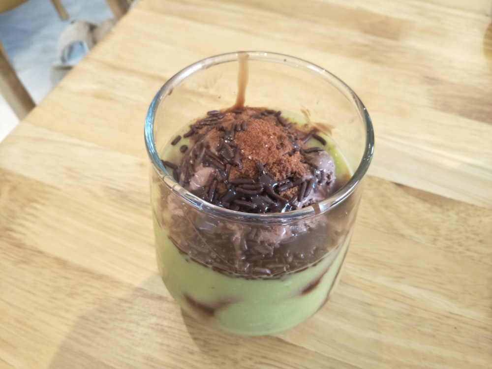 a glass filled with a dessert on top of a wooden table