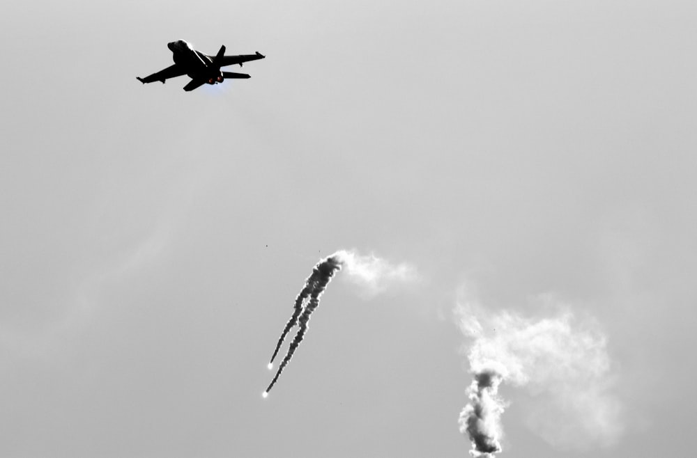 a jet flying in the sky with smoke coming out of it