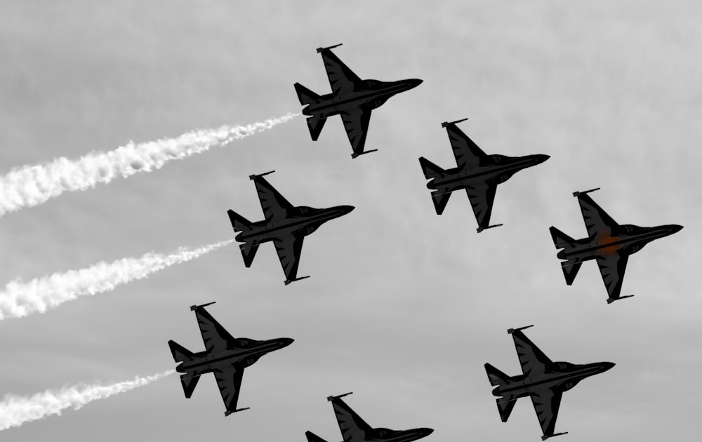 a group of fighter jets flying through a cloudy sky