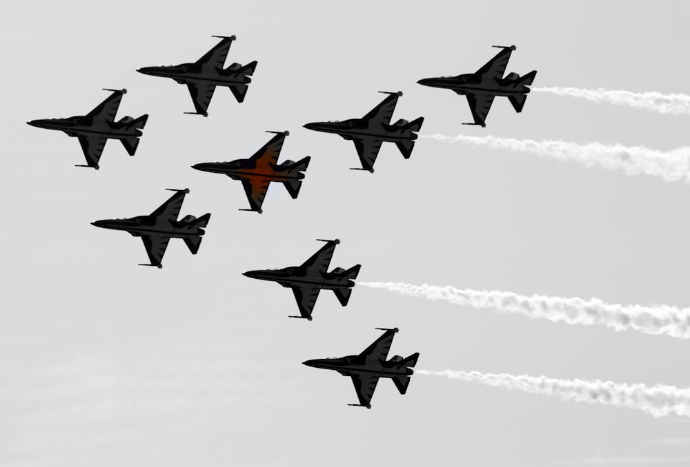 a group of fighter jets flying through a cloudy sky