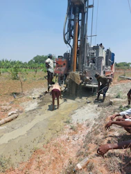 Engineers inspecting borehole infrastructure with rugged hills in the background.
