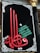 A decorative black banner prominently features ornate Arabic calligraphy in red and green. Intricate white designs frame the banner, adding an elegant touch. The script is set against a dark backdrop, highlighting its colors and details.