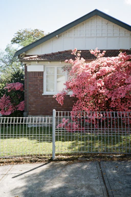 Cozy home with a welcoming porch surrounded by blooming flowers on a sunny day