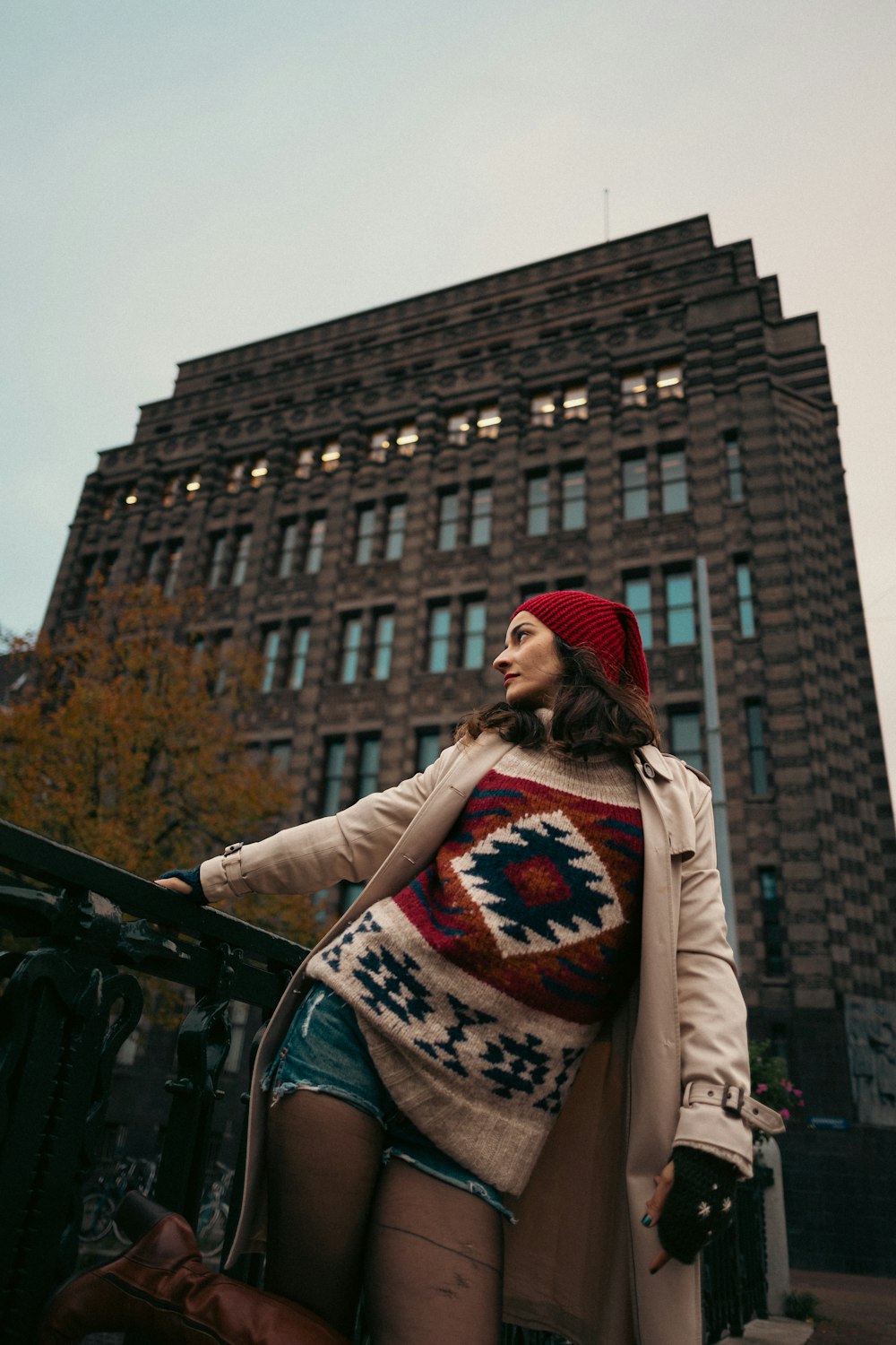 a woman standing on a railing in front of a tall building