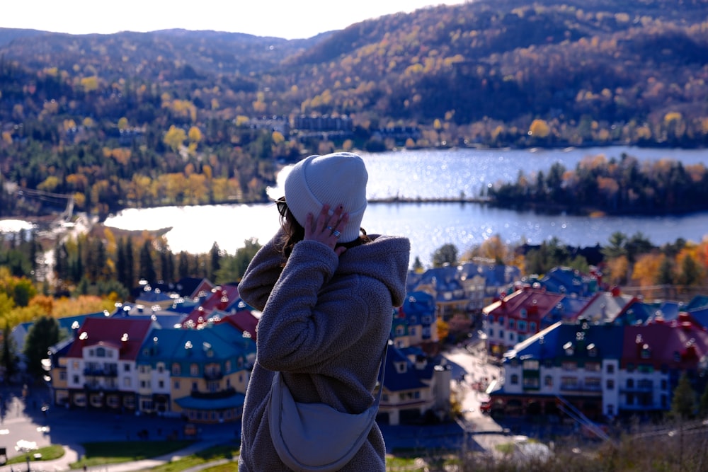 a woman standing on top of a hill next to a lake