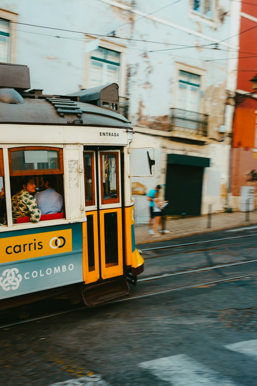 a trolley car with people inside traveling down a street