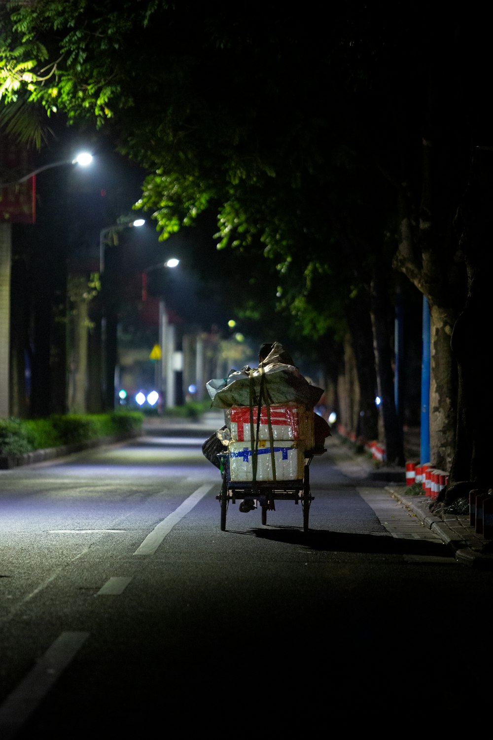 eine Person, die nachts mit einem Karren eine Straße entlang fährt
