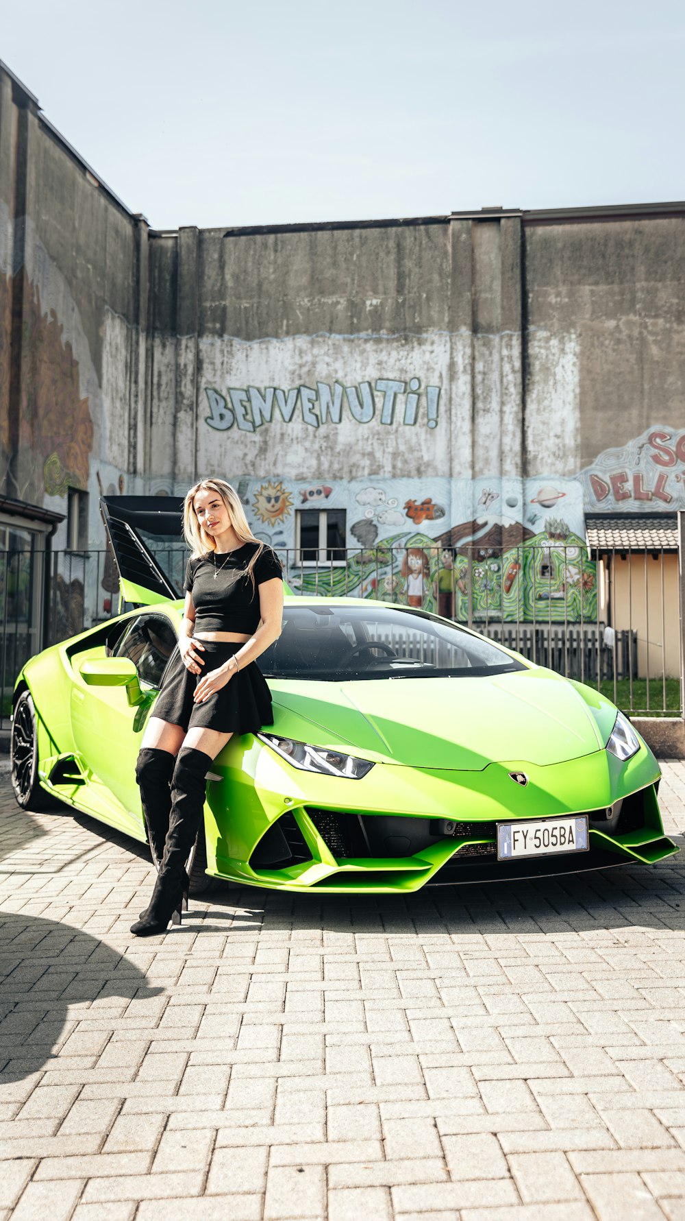 a woman sitting on top of a green sports car