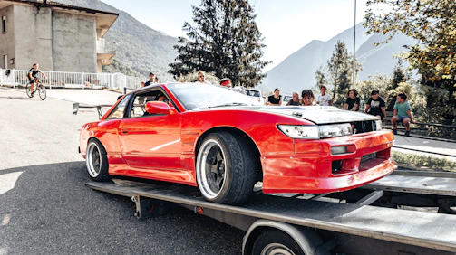 Close-up of a car securely strapped on a flatbed ready for transport from an auction yard.