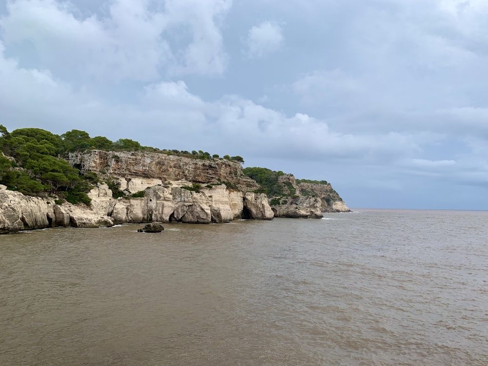 a large body of water with a cliff in the background