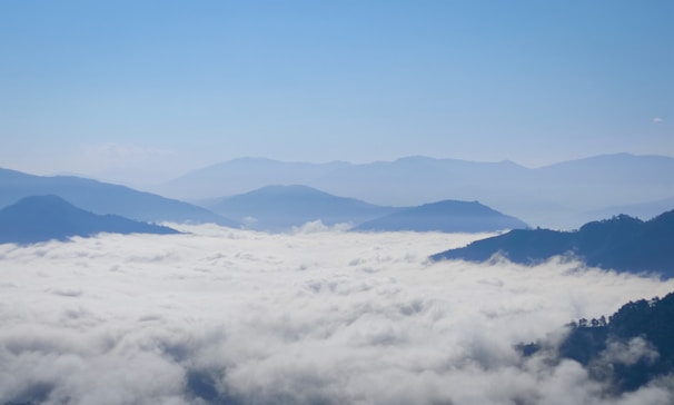 A breathtaking view of misty mountains under a blue sky.