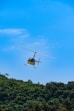 a helicopter flying over a lush green hillside