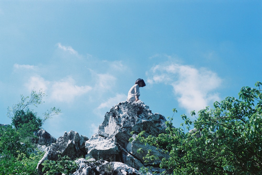 a person sitting on top of a rock formation