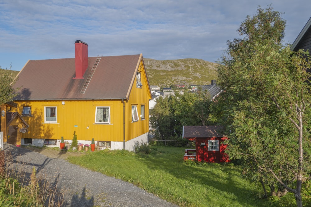 a yellow house with a red roof and a red fire hydrant