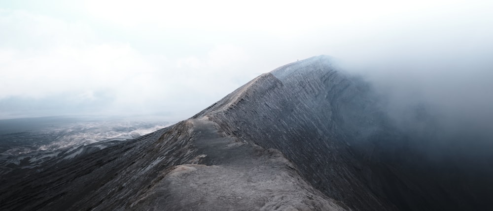 a very tall mountain in the middle of a foggy sky