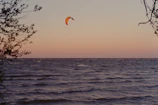 A vibrant kitesurfer gliding over turquoise waves along the Ceará coastline at sunset.