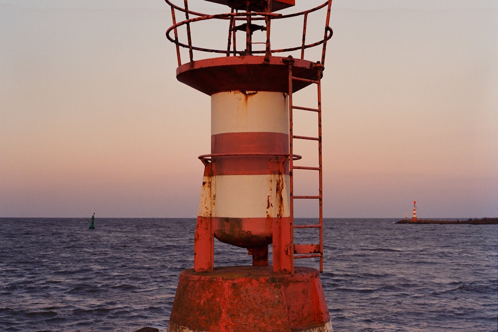 a red and white light house in the middle of the ocean