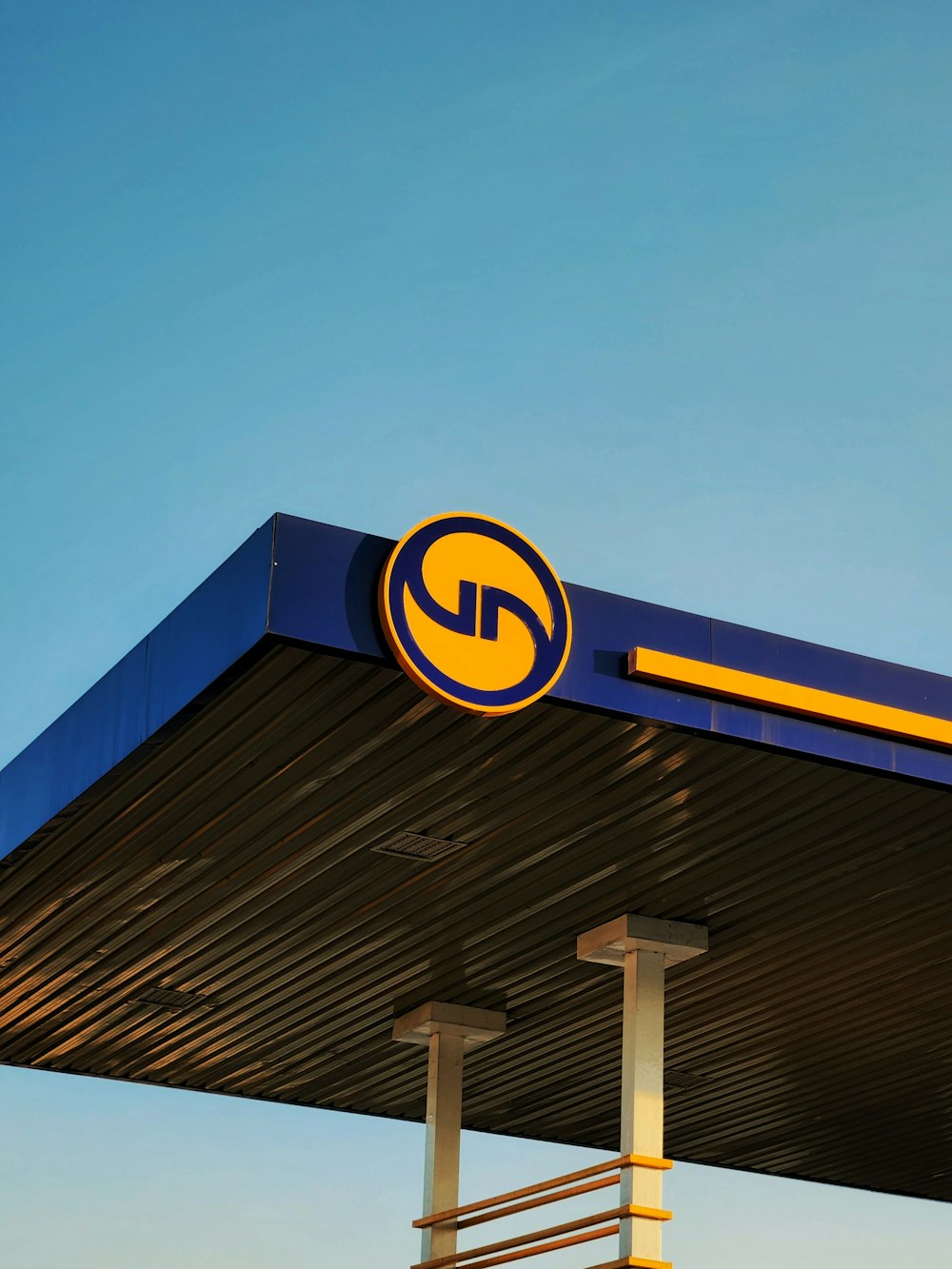 a blue and yellow gas station with a blue sky in the background