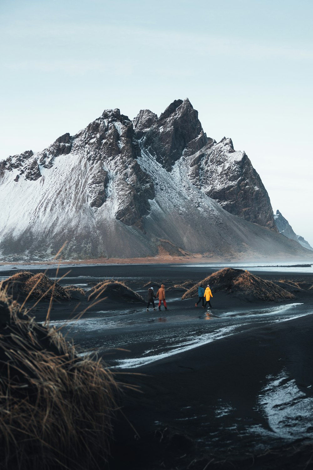 a group of people walking across a wet beach