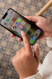 A friendly person holding a smartphone displaying social media apps Instagram and TikTok.