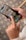A person is holding a smartphone, displaying a folder of social media apps including TikTok, LinkedIn, WhatsApp, Pinterest, YouTube, and Snapchat. The background consists of a patterned floor.