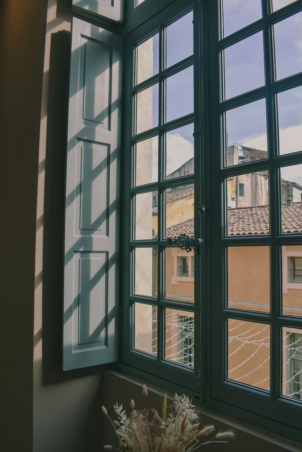 eine Vase mit Blumen vor einem Fenster