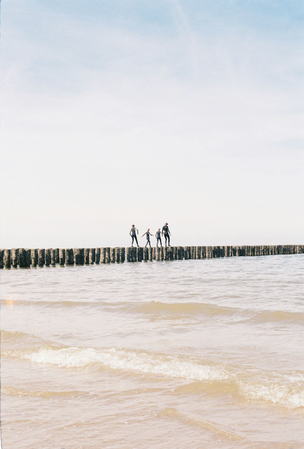 a group of people walking across a pier over water