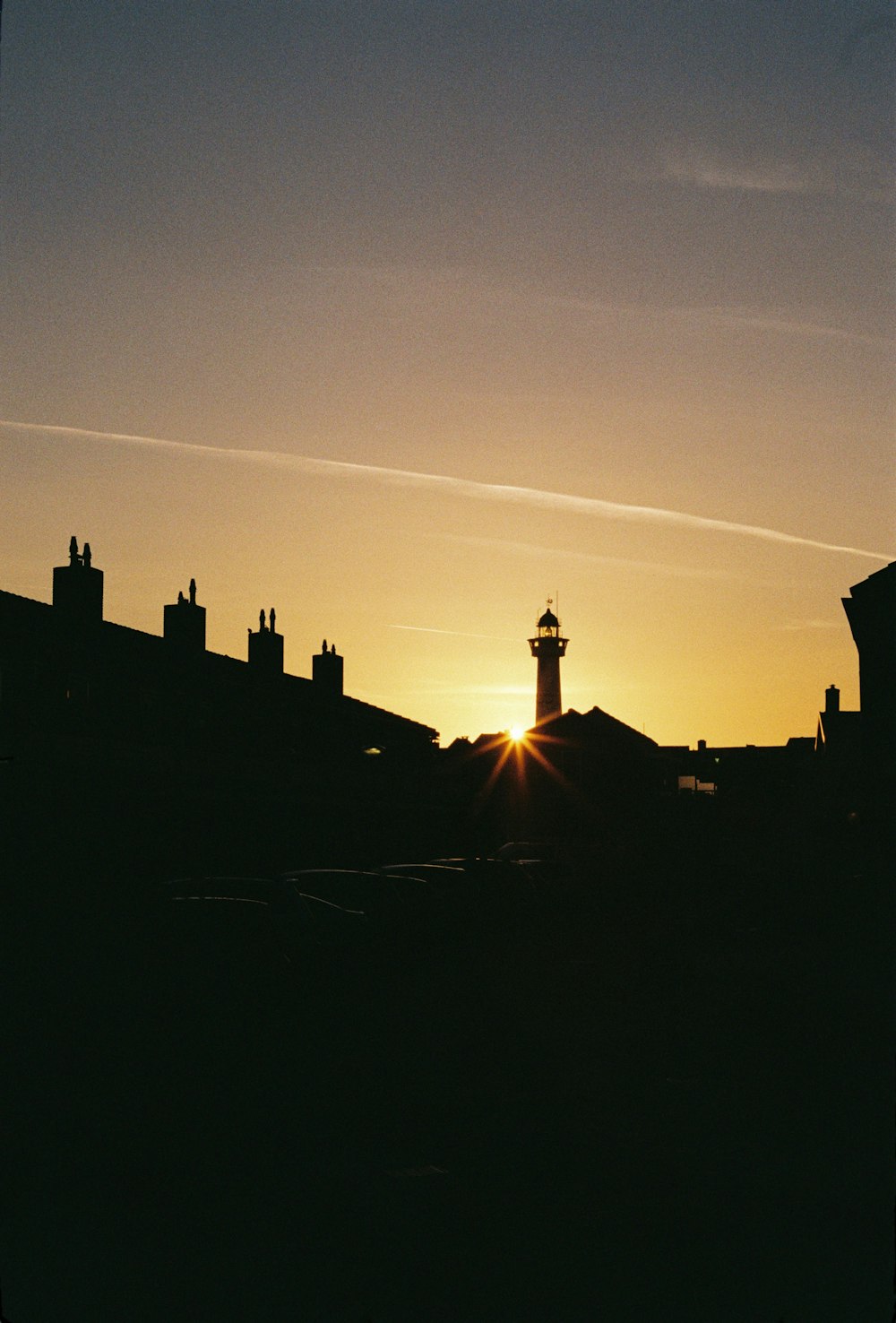 the sun is setting behind a building with a tower