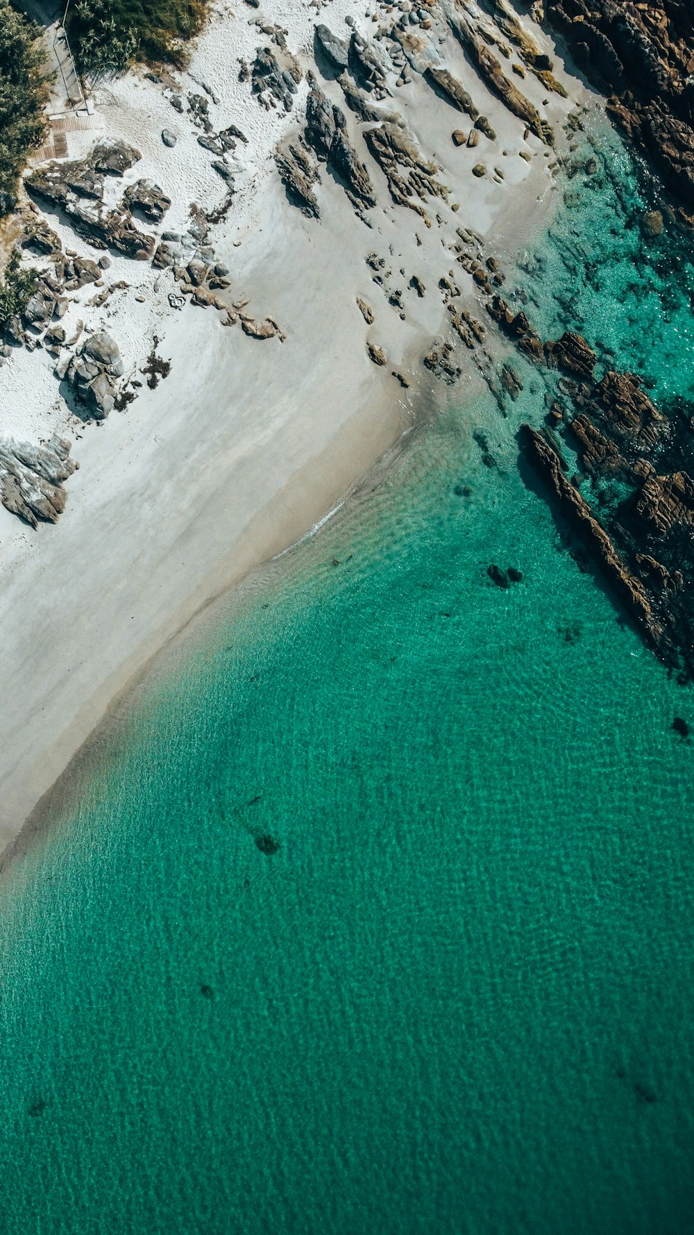 an aerial view of a sandy beach with clear blue water