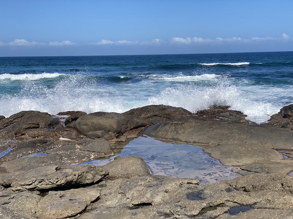 a body of water sitting on top of a rocky beach