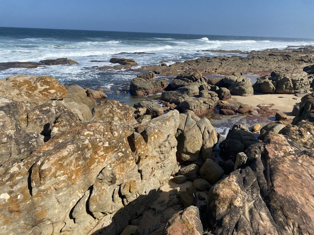 a rocky beach with a wave coming in from the ocean