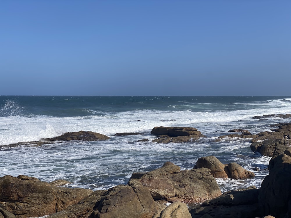 a person sitting on a rock near the ocean