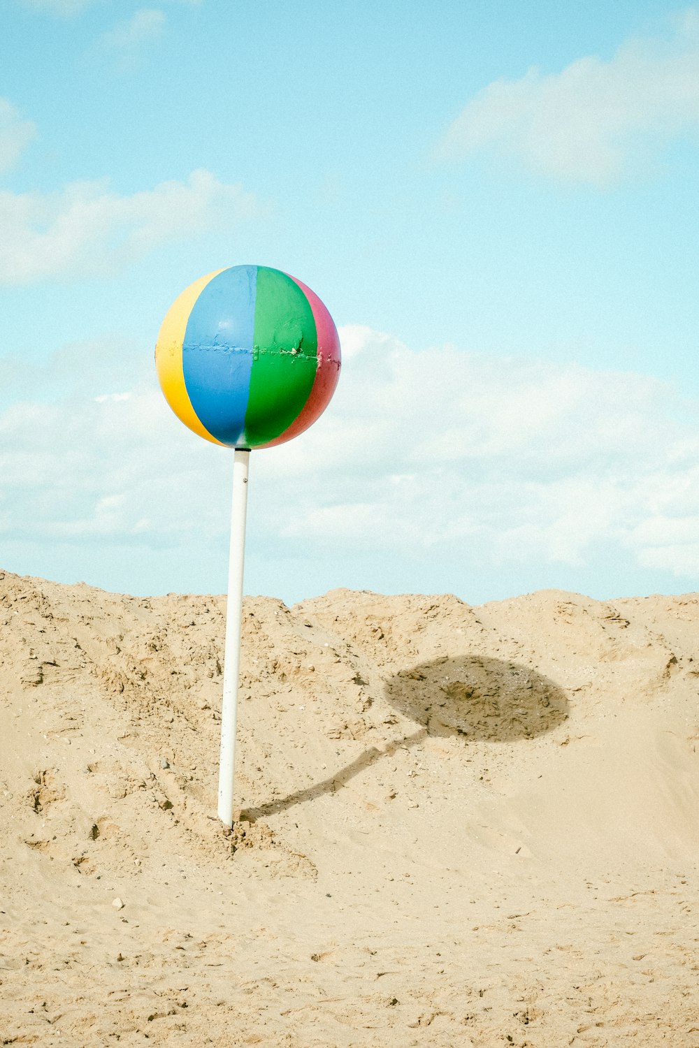 a colorful beach ball sitting on top of a white pole