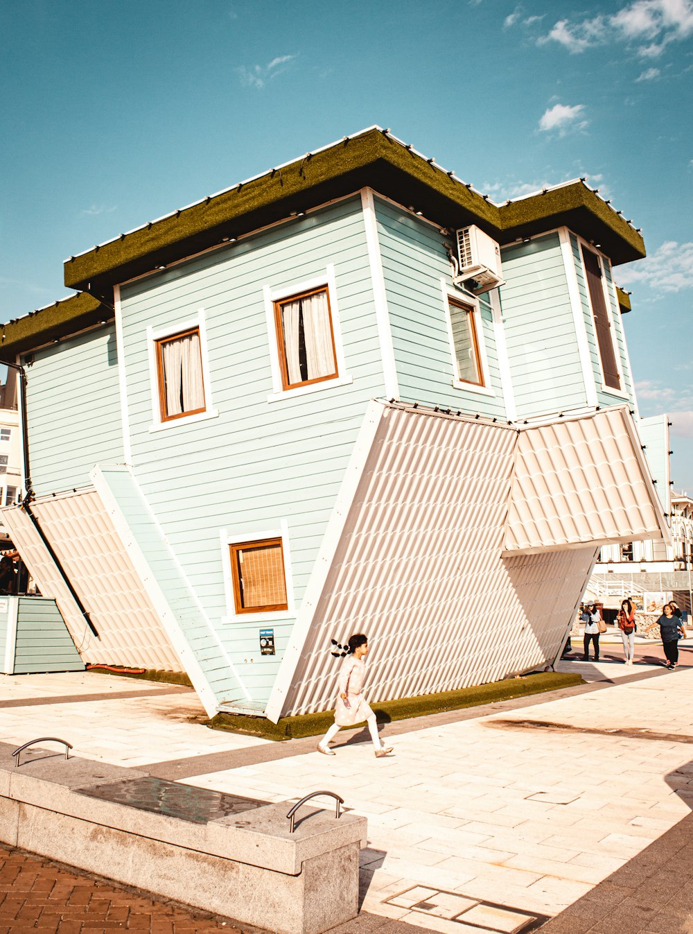 a person walking past a house shaped like a pyramid