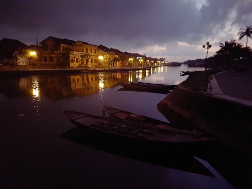 A peaceful riverside scene with traditional boats floating gently at sunset.