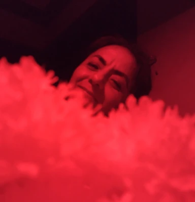 Close-up of a performer’s expressive face illuminated by soft red lighting.