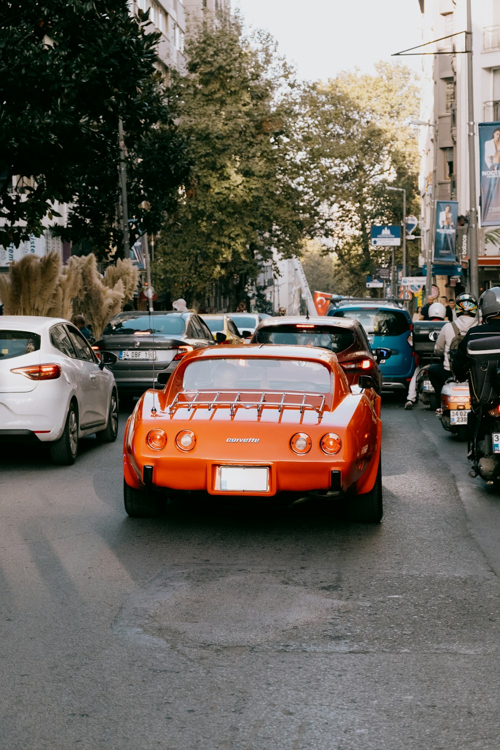 an orange sports car driving down a busy street
