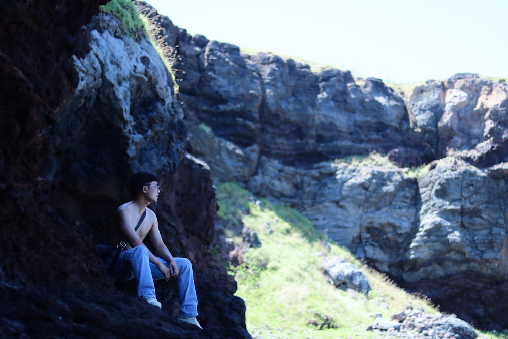 a person sitting on a rock near a cliff