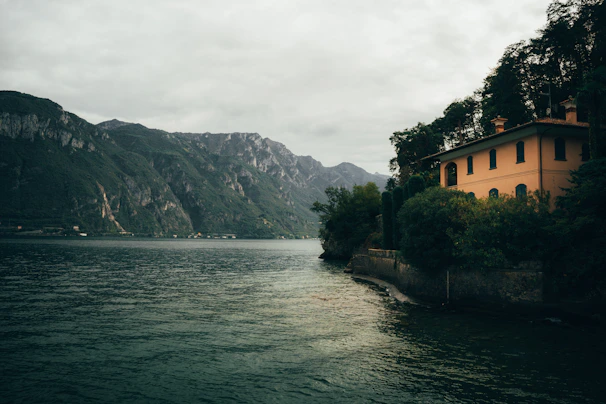 A welcoming portrait of Scott Buitta standing by a serene lakeside home in New Hampshire.
