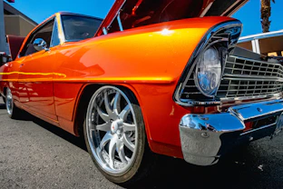 an orange classic car parked in a parking lot