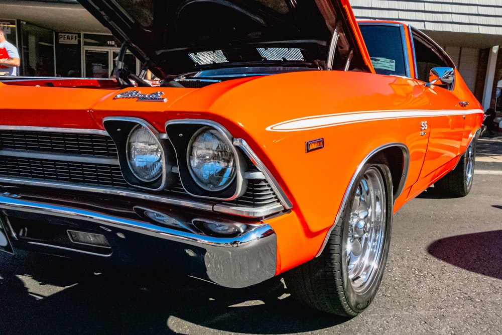 an orange classic car with its hood open