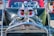A customized car with a vintage design features eye-catching modifications including large cartoonish red eyes on the engine, a skull decoration on the dashboard, and a metallic chain. The bright and shiny chrome parts reflect sunlight, giving it a polished look.