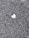 A rough textured asphalt surface with a single, small heart-shaped patch in a contrasting lighter color.