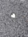 A rough textured asphalt surface with a single, small heart-shaped patch in a contrasting lighter color.