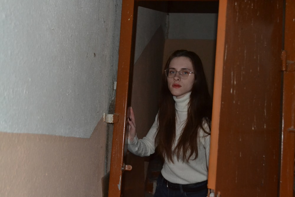 a woman with glasses standing in a doorway