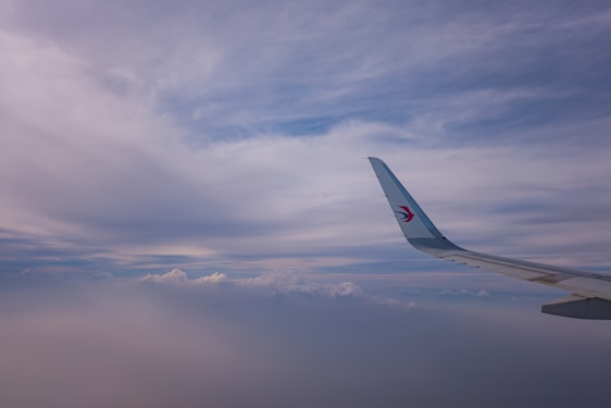 A sleek airplane soaring above clouds with a vibrant blue sky backdrop, symbolizing connection and innovation.
