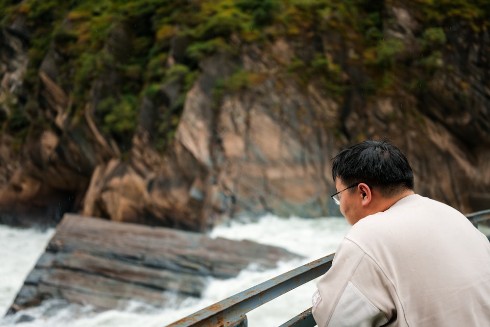 a man sitting on a rail looking at the water