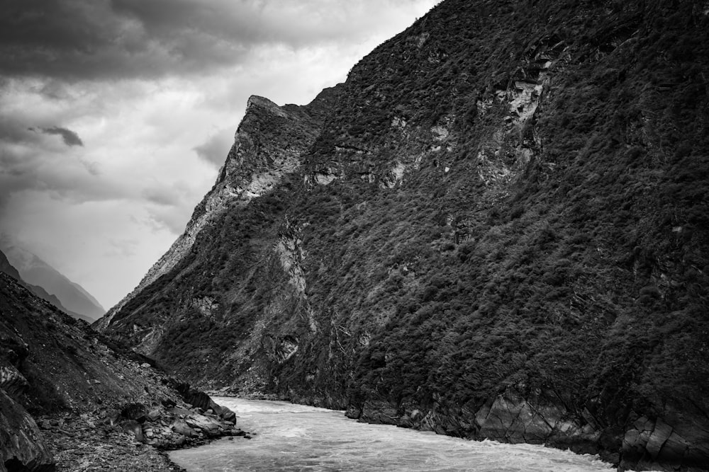 a black and white photo of a river in the mountains
