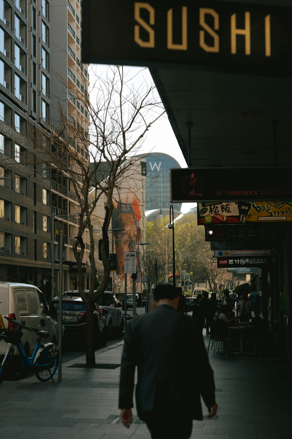 um homem caminhando por uma rua ao lado de prédios altos